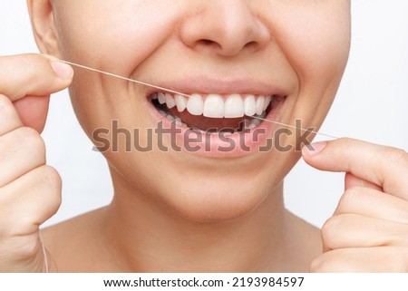 Cropped shot of a young attractive caucasian woman flossing her teeth after meal with dental floss isolated on a white background. Dental health care, oral hygiene, evening routine. Dentistry concept Royalty-Free Stock Photo #2193984597