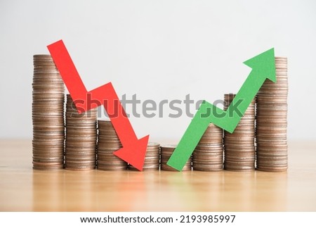 Stack coins and arrow red green graph chart volatility up and down on wooden table background. Business, financial and investment concept. Risk, fluctuation in stock market and cryptocurrency.