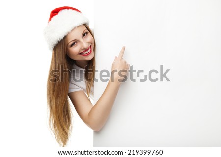 Beautiful christmas woman in santa hat pointing empty board, isolated on white background