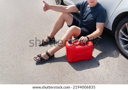The driver wants to refuel in an empty car tank, an empty red canister on the side of the road. Selective focus, noise. Stops on the road. Fuel problem, force majeure Royalty-Free Stock Photo #2194006835
