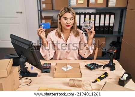 Young hispanic woman working at small business ecommerce with online payment relaxed with serious expression on face. simple and natural looking at the camera. 