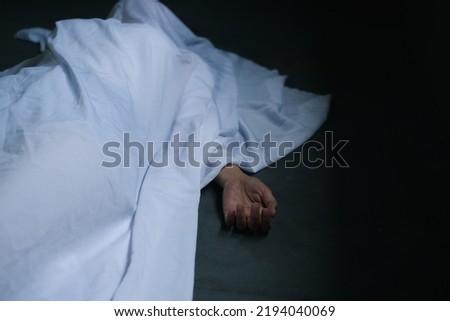 Hand of dead woman lying down under white cloth covered death body from murder at house of victim,Horror and crime scene. Royalty-Free Stock Photo #2194040069