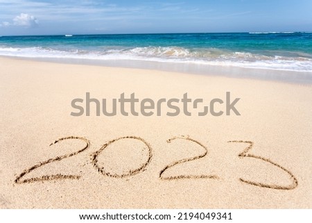Happy New Year 2023, lettering on the beach with wave