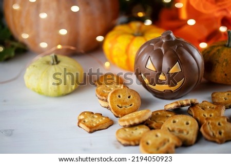 Close up of Halloween cookies and chocolate on light wooden table