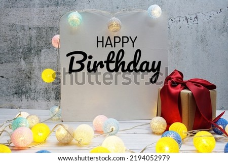 Happy Birthday text message with LED cotton ball decoration on wooden background