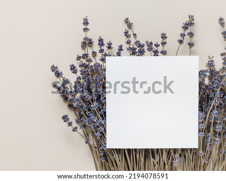 Empty mockup paper card on lavender flowers, top view, copy space. Invitation or greeting card with copy space, minimal style business template.