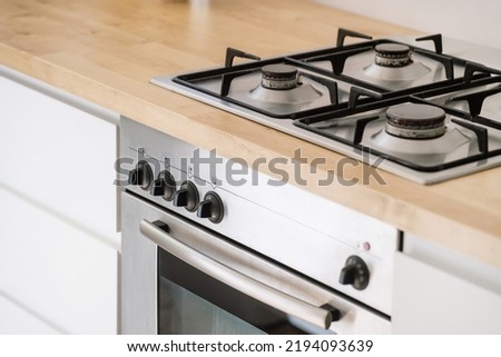 stainless steel gas cooker built in wooden countertop and electric oven with control panel at contemporary kitchen Royalty-Free Stock Photo #2194093639