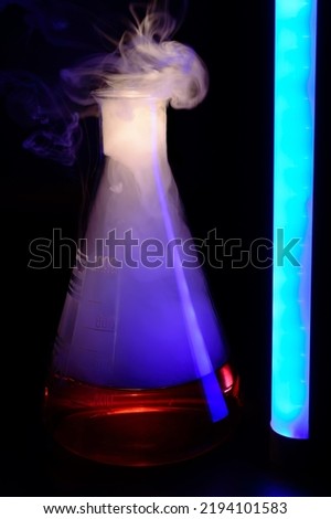 Strong chemical reaction with a lot smoke and vapors inside Erlenmeyer flask. School chemical experiment Vessel with a red liquid and purple smoke. Background picture.