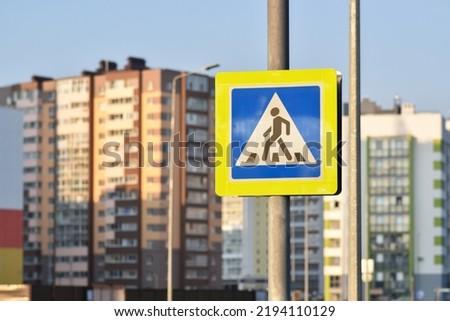 A road sign warns a pedestrian against the background of houses.