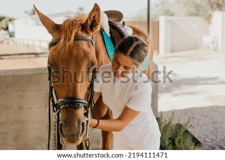 15 year old girl putting the bridle on a pony Royalty-Free Stock Photo #2194111471
