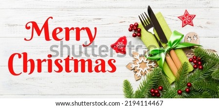 Merry Christmas text. Top view of christmas decorations on wooden background. Fork and knife on napkin tied up with ribbon and empty space for your design. New year pattern concept.