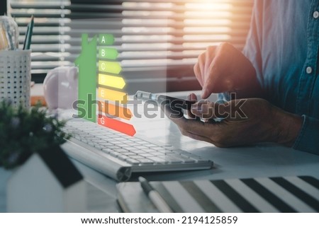 Person hand using laptop computer with house icon energy efficiency scale image on office desk, Concept of ecological and bio energetic house. Energy class. Royalty-Free Stock Photo #2194125859