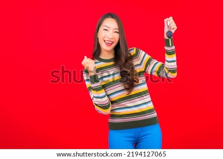 Portrait beautiful young asian woman with car key on red isolated background