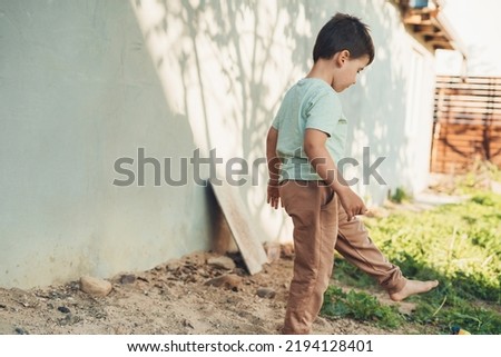Boy stepping through the garden of the house, spending his vacation day active and interesting. Summer outdoors activity for kids. Summer sunny day.