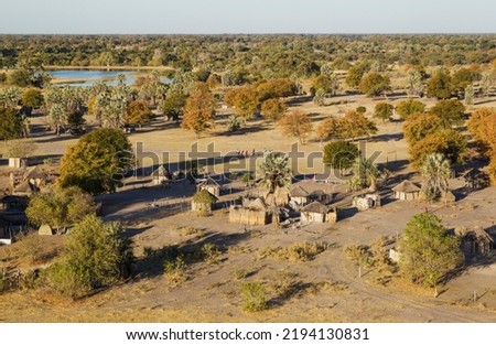 Native village just outside of the protected area, prominent a group of young men getting ready for a football match, aerial view, Okavango Delta, Botswana
