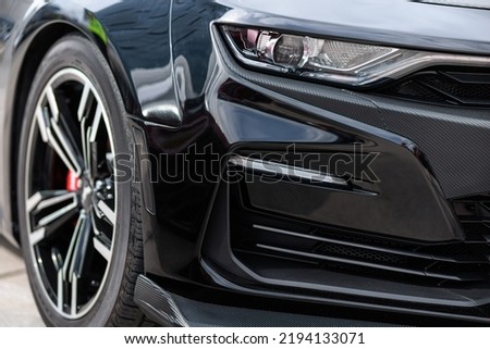 Close up of headlight detail of luxury sports car with reflection on red paint after wash and wax. Front view of supercar. Concept of car detailing and paint protection background. Royalty-Free Stock Photo #2194133071
