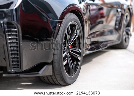 Close up of headlight detail of luxury sports car with reflection on red paint after wash and wax. Front view of supercar. Concept of car detailing and paint protection background. Royalty-Free Stock Photo #2194133073