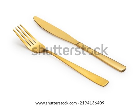 Gold knives and forks placed against a white background. Beautiful gold cutlery.  Royalty-Free Stock Photo #2194136409