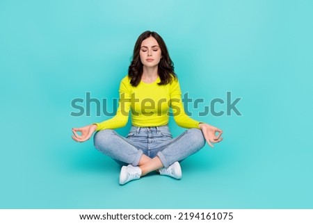 Full size photo of charming girl sit floor crossed legs closed eyes meditate isolated on teal color background
