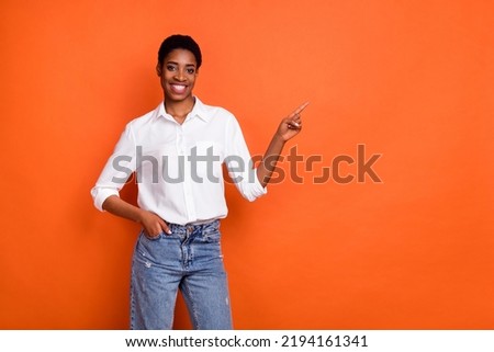 Photo of good mood nonbinary person point finger empty space promote product isolated on orange color background