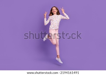 Full body portrait of excited active pupil jump arms fingers demonstrate v-sign isolated on purple color background