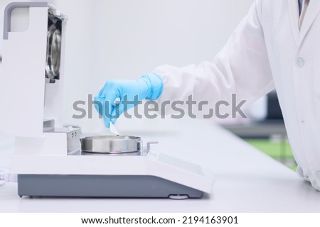 Unidentified operator or chemist is testing moisture or water content in sample with automatic moisture balance in the laboratory. Concept of quality control in pharmaceutical industry. Royalty-Free Stock Photo #2194163901