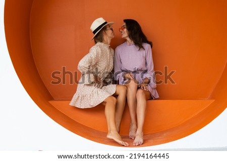 Two young beautiful smiling hipster female in trendy summer sundress.Sexy carefree women posing on the street orange background. Positive models having fun Royalty-Free Stock Photo #2194164445