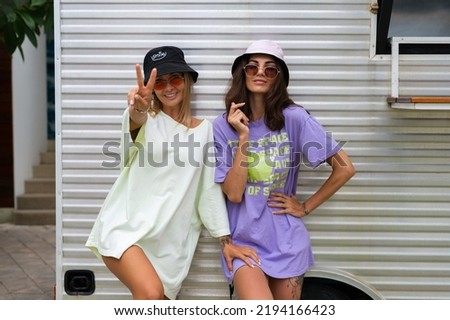 Two young positive stylish hipster smiling girl friends in trendy panama and trendy sunglasses posing outdoor, having fun, laugh
