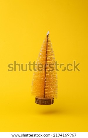Decorative Christmas tree flying in antigravity on yellow background with shadow. Levitation object in the air. Creative minimal layout