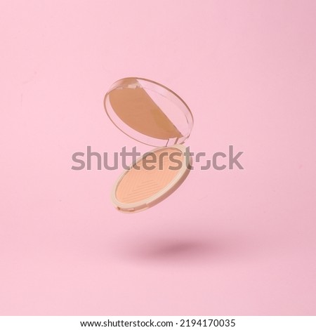 Powder box flying in antigravity on pink background with shadow. Levitation object in the air. Beauty and fashion concept. Creative minimalist layout