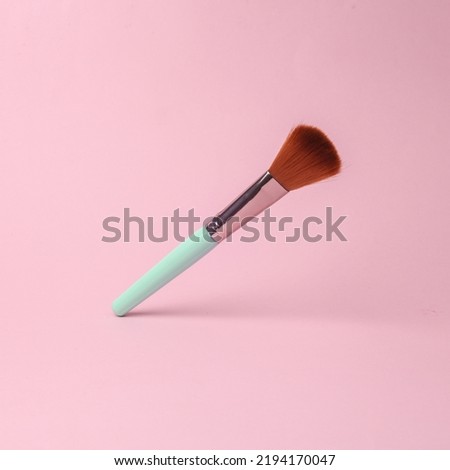 makeup brush flying in antigravity on pink background with shadow. Levitation object in the air. Beauty and fashion concept. Creative minimalist layout