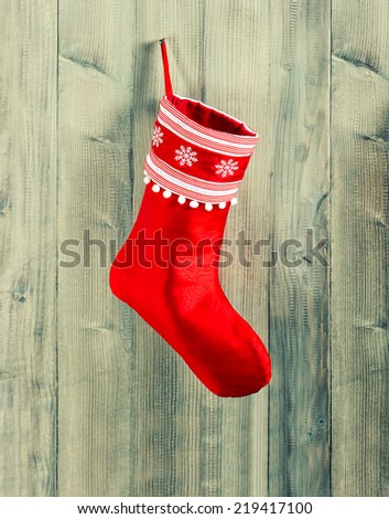 christmas stocking. red sock with white snowflakes hanging over rustic wooden background