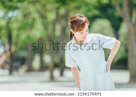 A woman in a white coat with back pain