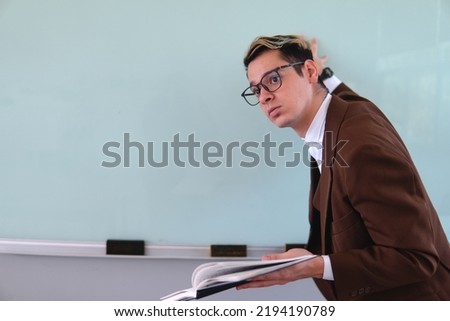 Elegant teacher. A blond Caucasian man dressed elegantly in a brown jacket, shirt and glasses. Man dressed in sack in front of a school group. High quality photo
