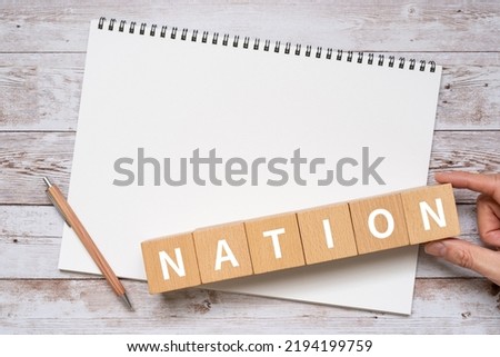 Wooden blocks with "NATION" text of concept, a pen, and a notebook.