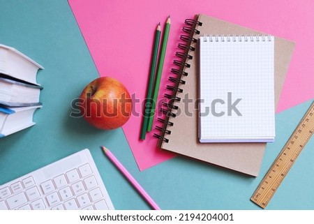 Back to school concept flat lay photo. Books, computer keyboard, notepad, pencils, wooden ruler, apple on a table