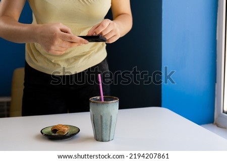 Closeup of women's hands making photo of food on mobile phone while sitting in comfortable restaurant, female taking pictures with cell phone camera dessert during rest in cafe
