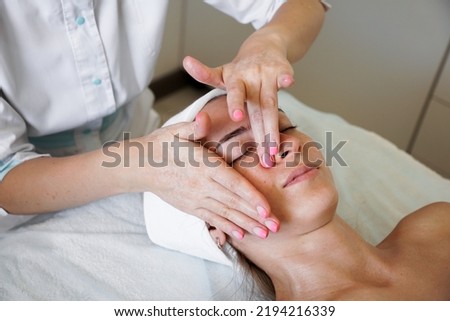 Pretty yanog woman receiving face massage, closeup photo. Beauty treatments. Beautician