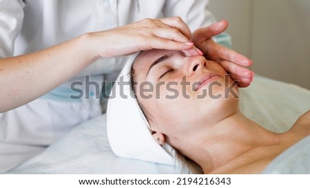 Pretty yanog woman receiving face massage, closeup photo. Prevention of skin aging and wrinkles.