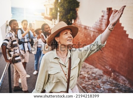Travel, education and a teacher with students on school field trip, on urban tour. Woman, city guide and group of happy tourists, pointing at local architecture and learning on international holiday Royalty-Free Stock Photo #2194218399