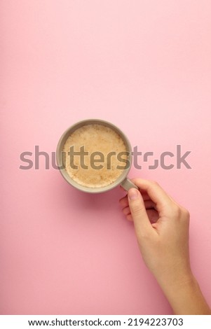 Female hand hold coffee cup on pink background. Top view