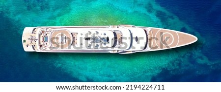 Aerial drone ultra wide top down photo of luxury exotic yacht with wooden deck and helipad anchored in paradise turquoise bay