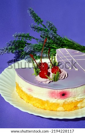 Cake with lavender, a mousse dessert with an exotic taste on a white plate on a purple background. Garnished with cherries and rosemary sprigs.