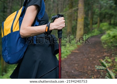 Woman solo traveler with trekking poles in pine forest on the path. GO Everywhere Royalty-Free Stock Photo #2194240753