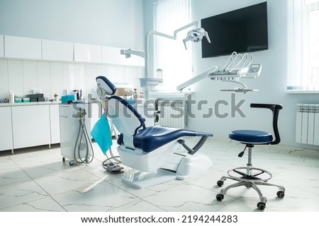 Dental equipment in dentist office in new modern stomatological clinic room. Background of dental chair and accessories used by dentists in blue, medic light. Copy space, text place Royalty-Free Stock Photo #2194244283