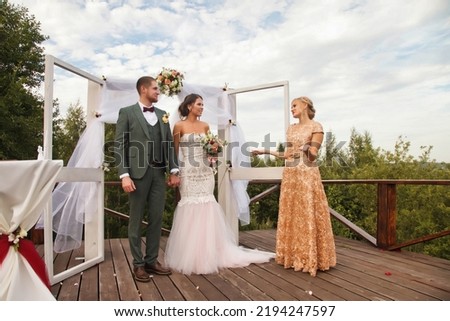 Registrar having official wedding ceremony next to Bridal couple. Bride and groom on wed irish style event in country outdoors. Marriage registration office and happiness married. Copy text space Royalty-Free Stock Photo #2194247597
