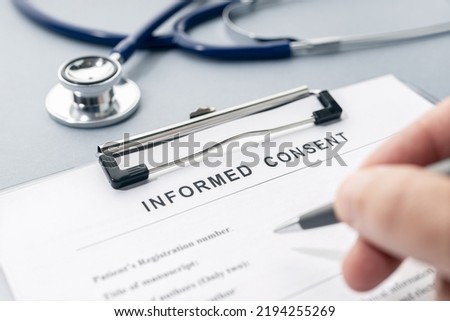 Hand filling a Informed Consent form and stethoscope on desk Royalty-Free Stock Photo #2194255269