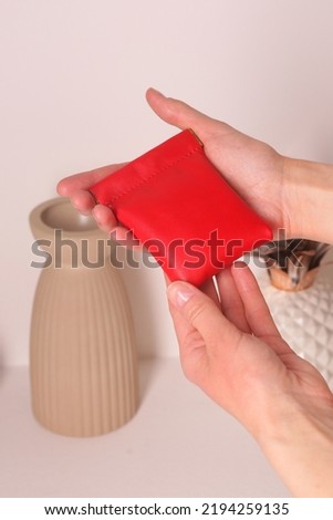  leather red coin case with in woman hands close up photo on white wall background
