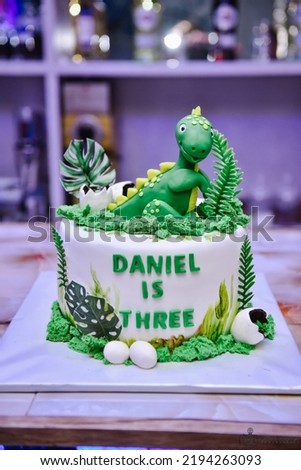 Children's holiday white cake decorated with mastic figurines of dinosaurs in the Jurassic period jungle. Concept ideas desserts for kids