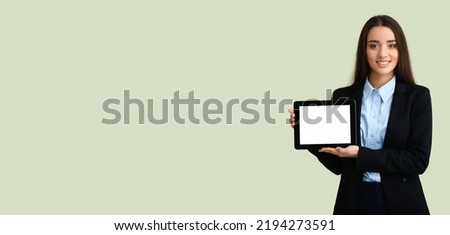 Happy young businesswoman holding tablet computer on light color background with space for text